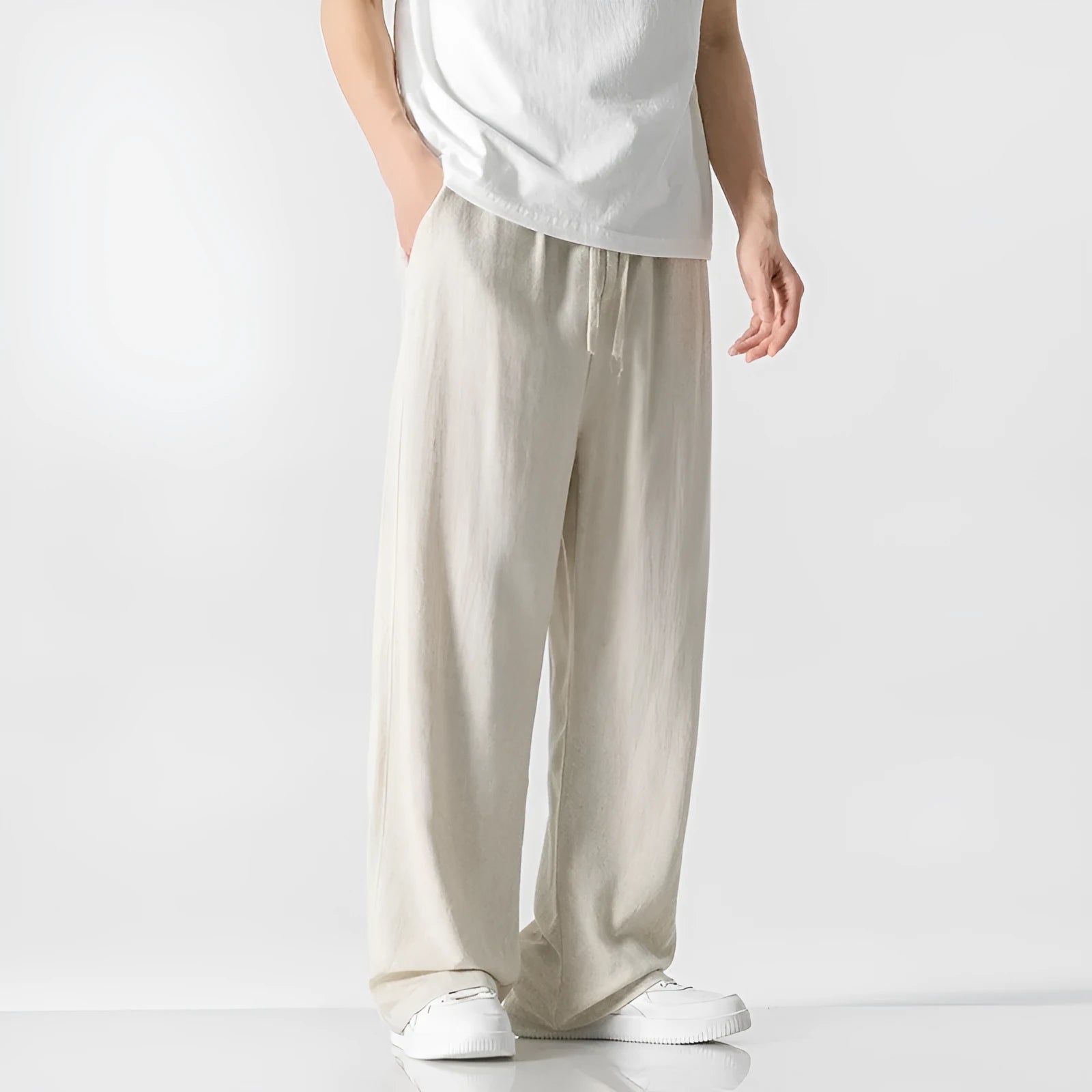 Man wearing beige straight-leg cropped bamboo fibre trousers with a drawstring waist on a summer day.