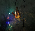 Tapered butterfly-shaped solar garden lantern made of iron, emitting a warm white light.