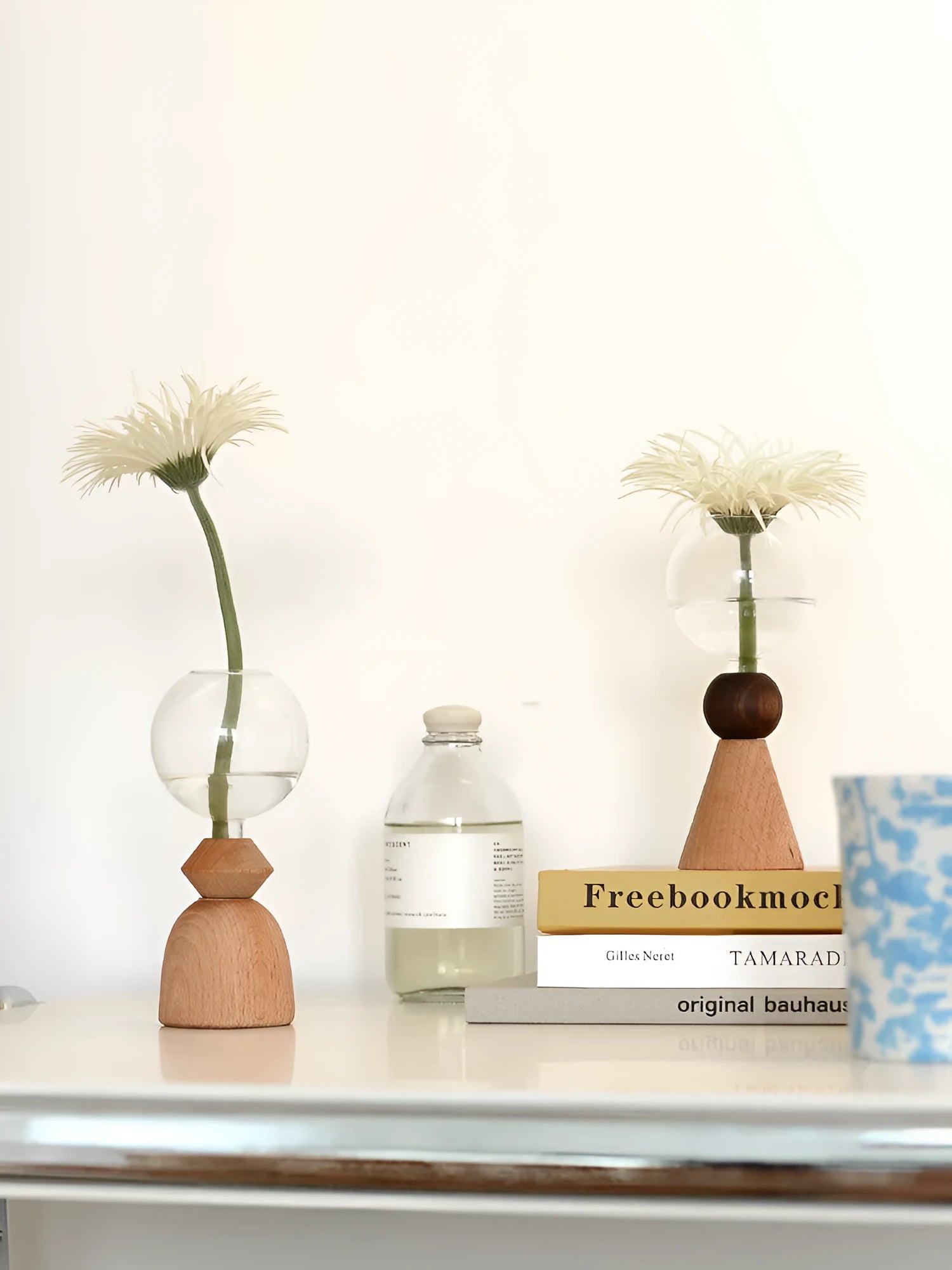 Small clear geometric bubble glass vase on a wooden base, shown with a single flower stem.