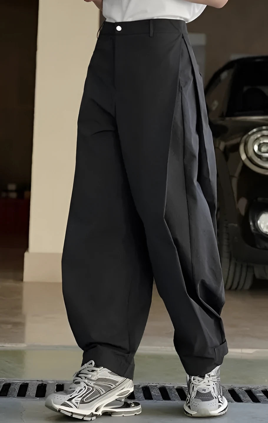 Black high-waisted women's trousers with front pleats and a loose wide-leg silhouette on a model.