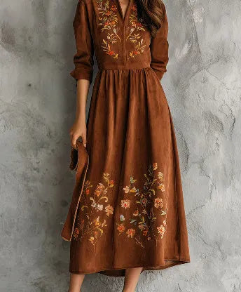 Brown suede-look midi dress with detailed floral embroidery on the bodice and hem, featuring three-quarter sleeves.