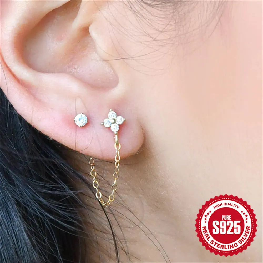 Close-up of a geometric S925 sterling silver clip-on earring featuring a diamond flower and a delicate gold-plated chain tassel.