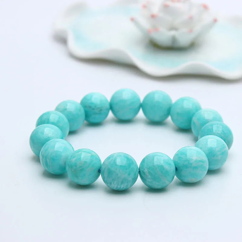 Natural blue-green amazonite gemstone bracelet with round polished beads on a white background.