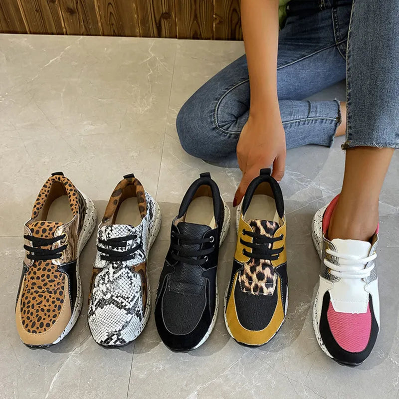 Women's black suede wedge sneakers with a round toe and low-cut design on a wooden floor.