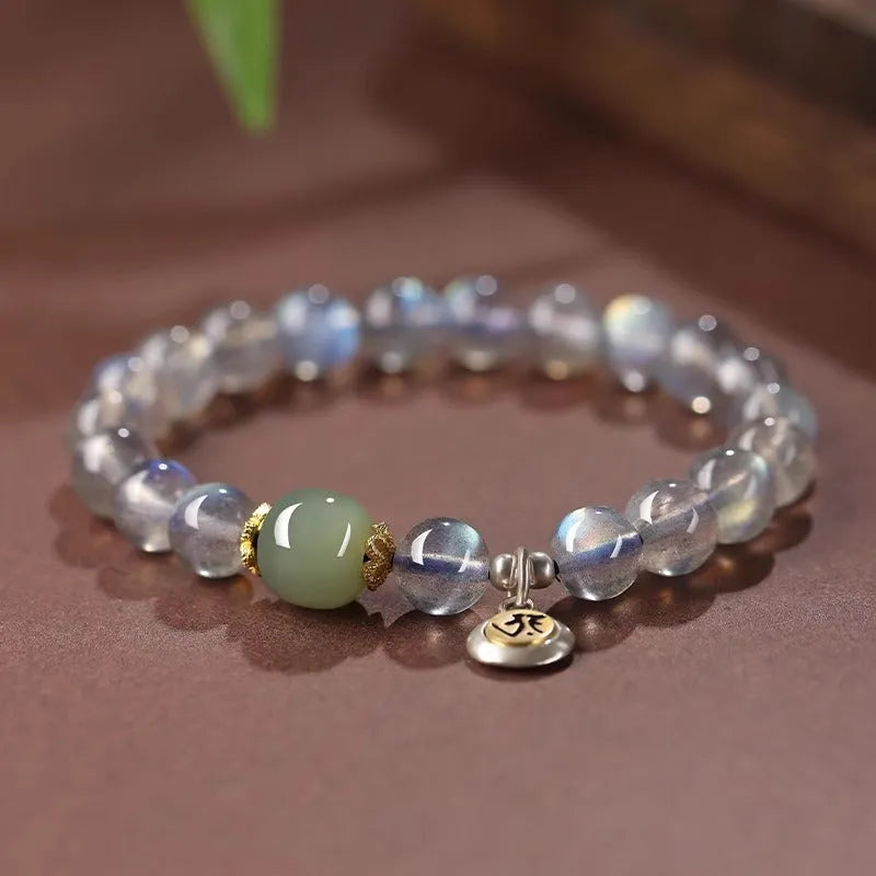 Moonstone bracelet with 8mm beads and a silver Guanyin mouse zodiac charm on a black background.