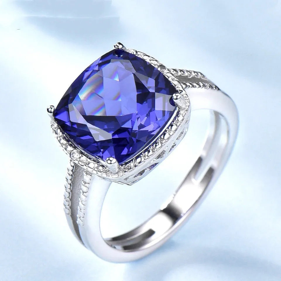 A blue tanzanite stone set in a sterling silver women's ring on a white background.
