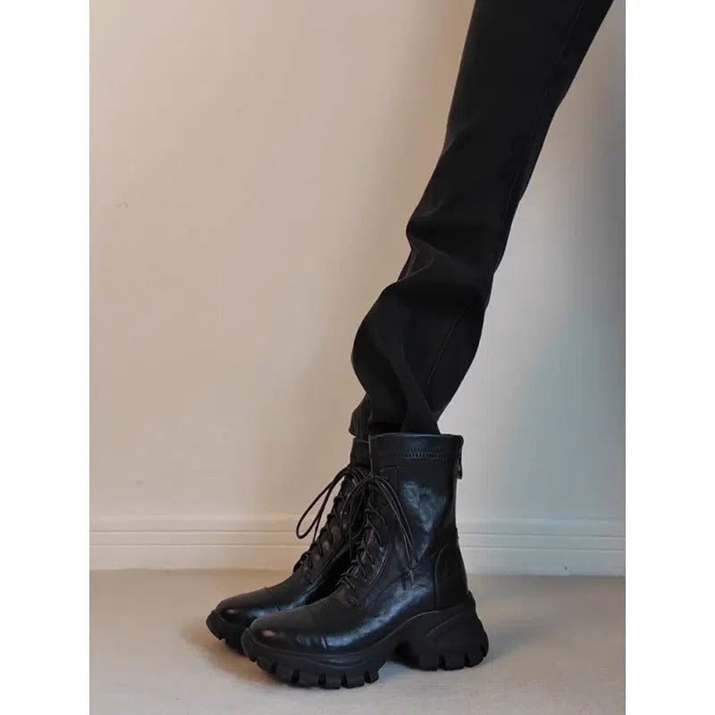 Black thick-soled motorcycle boots with back zipper, lace-up front, round toe, and rubber sole on a neutral background