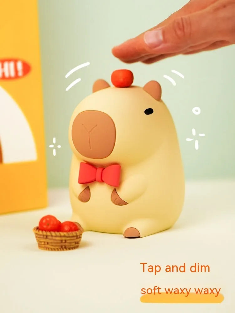 Small capybara-shaped night lamp in silicone and plastic, shown with USB cable.
