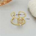 Gold-coloured adjustable open ring with a U-shaped asymmetric design on a hand.