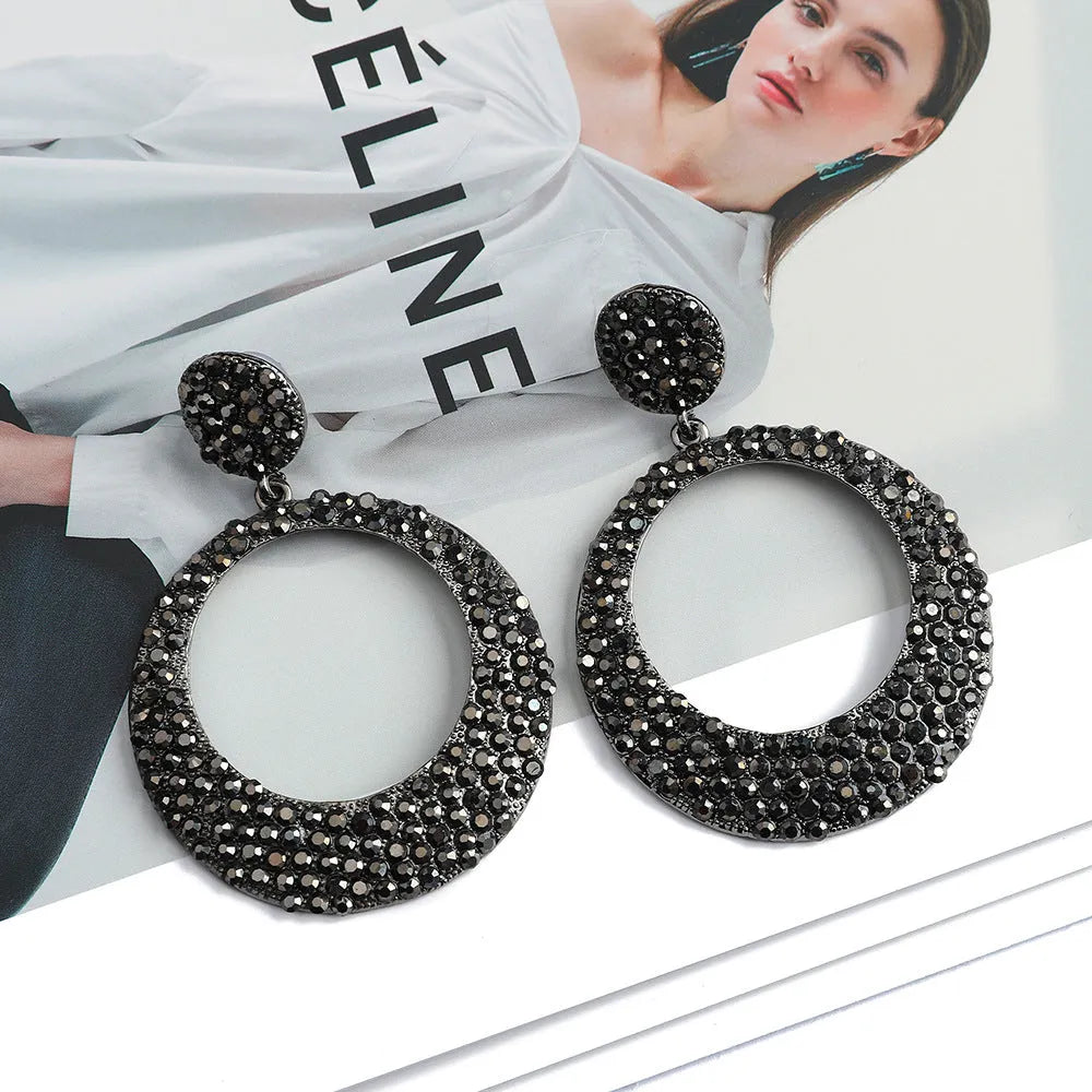 A pair of large round cartoon pendant earrings made from metal alloy, shown in a colour finish.