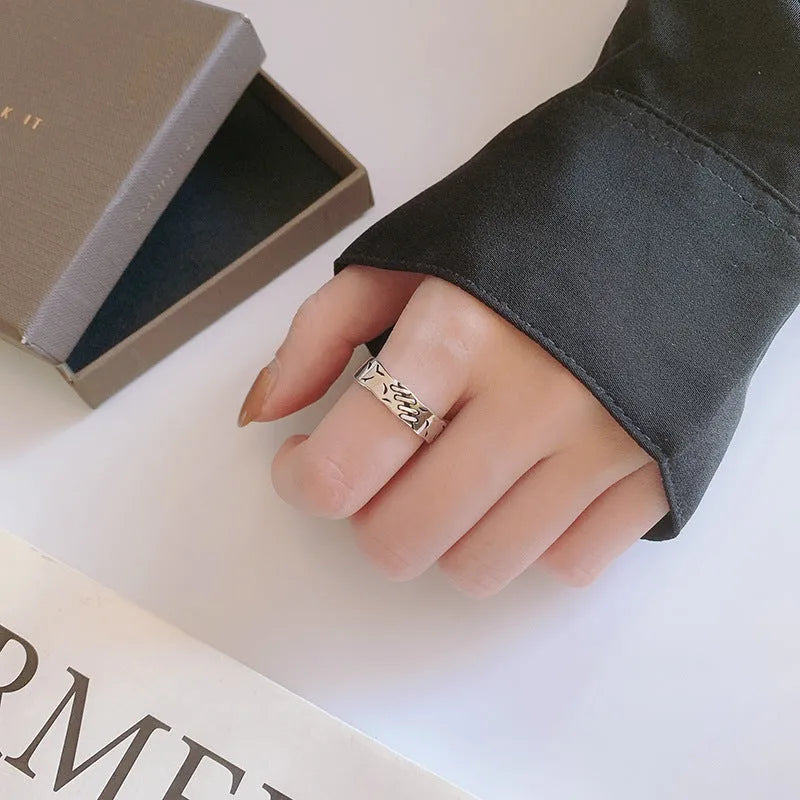 Black geometric copper ring with an adjustable opening on a plain background.