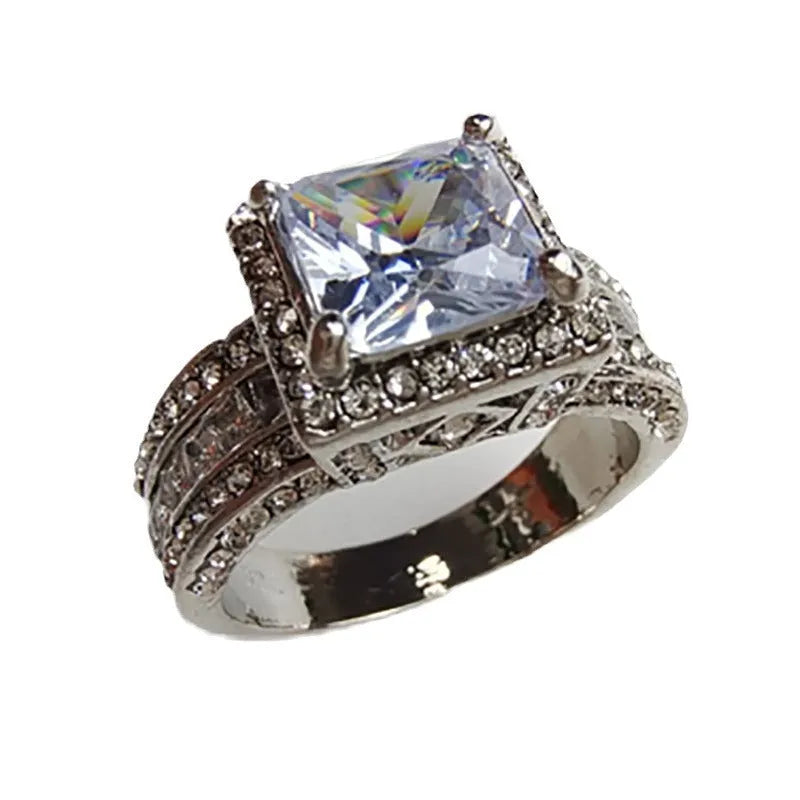 A geometric silver-tone women's ring with a round design element on a model's hand.