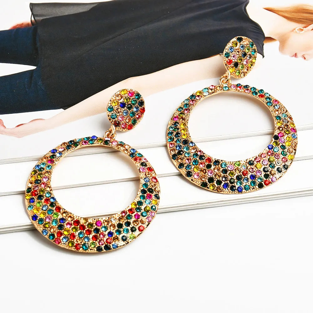 A pair of large round cartoon pendant earrings made from metal alloy, shown in a colour finish.