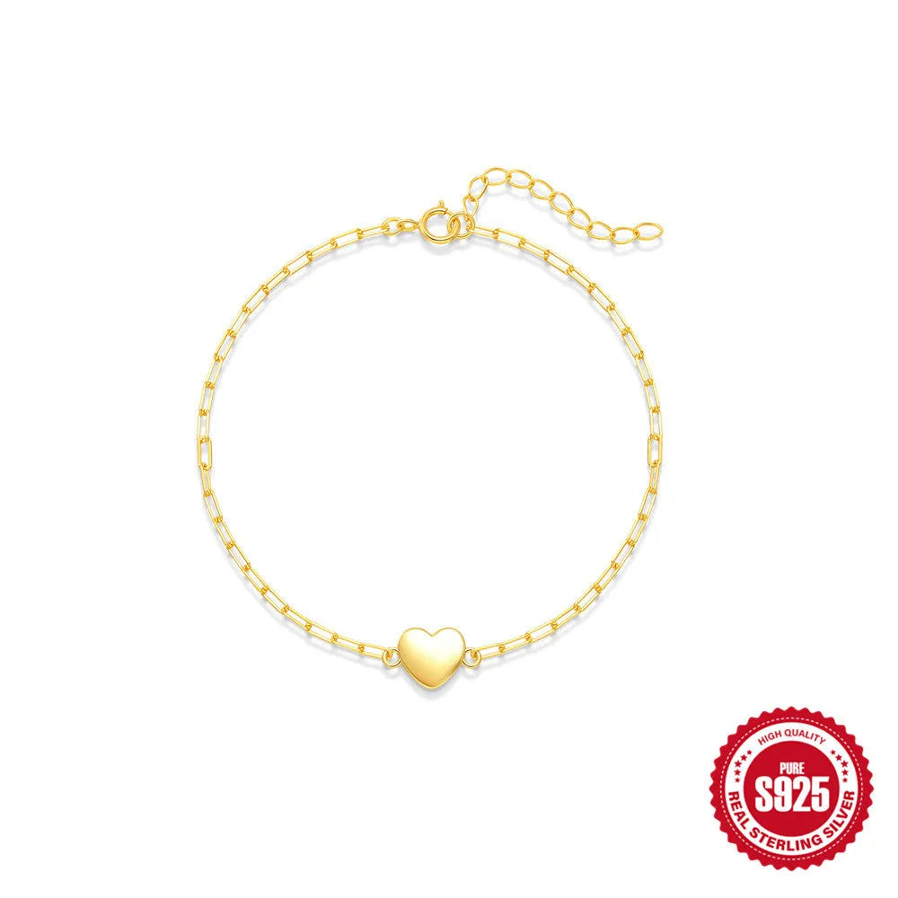 Close-up of a women's sterling silver bracelet with a glossy gold heart charm and lobster clasp.