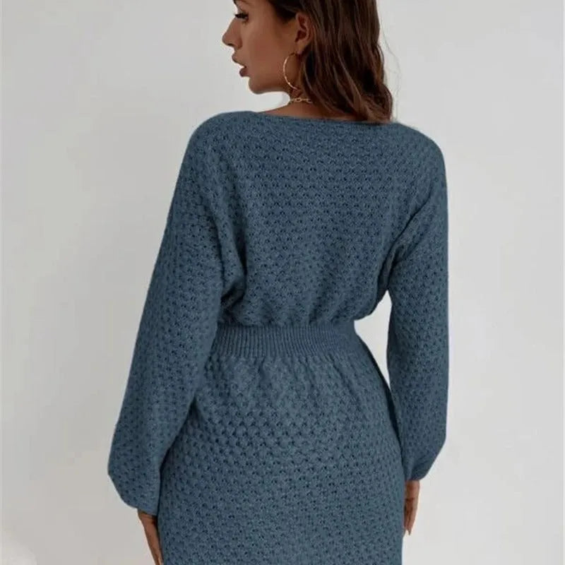 Blue knitted dress with fitted waist, round neck, long sleeves, and white crocheted flower details.