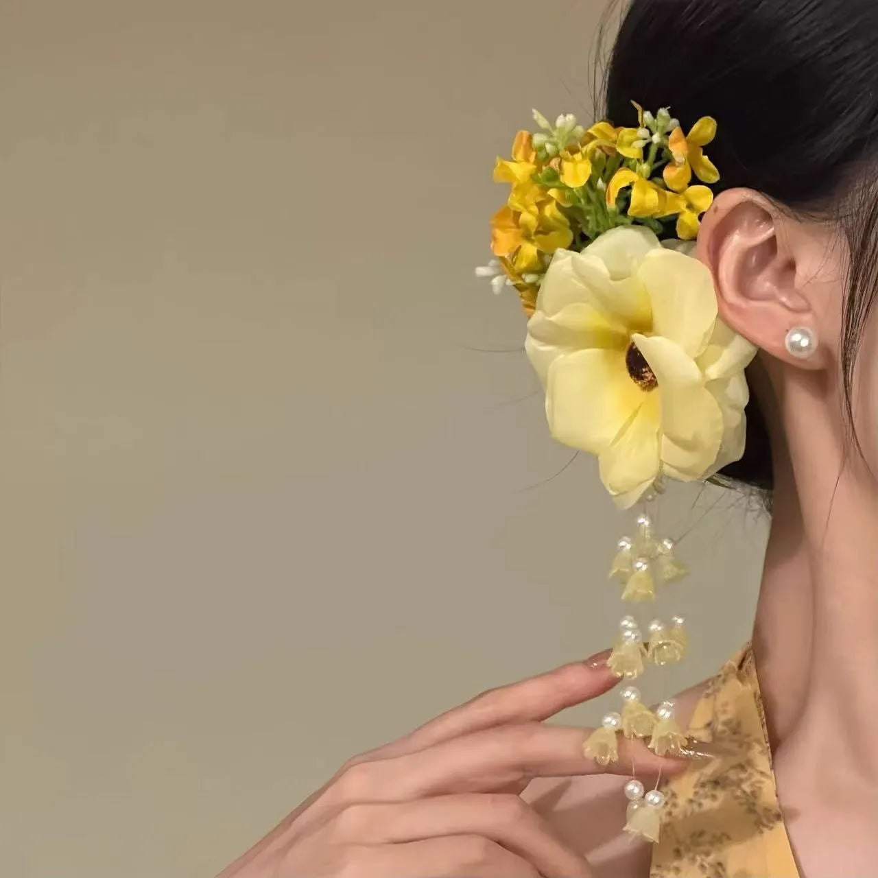 Handmade yellow and purple floral hair clip with pearl details and a tassel on a metal side clip.