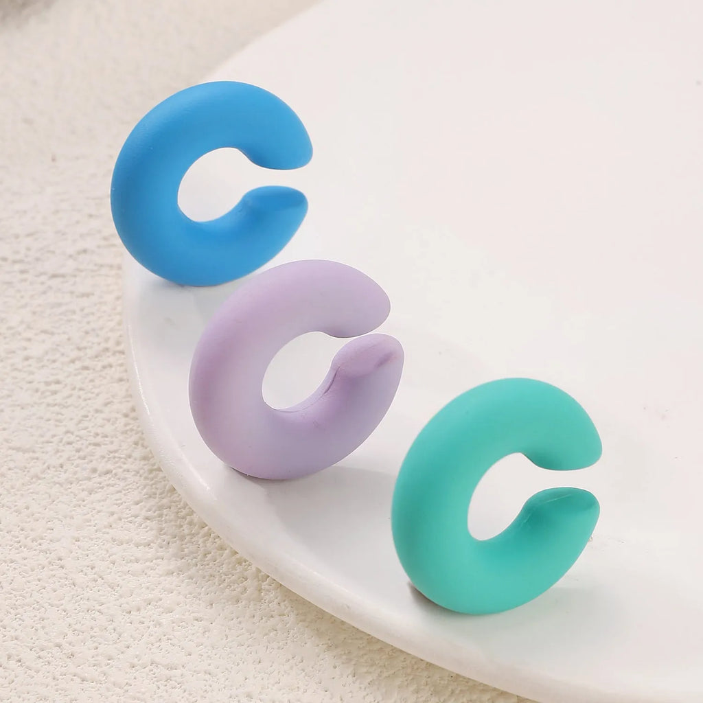Close-up of matte finish, coarse round C-shaped clip-on earrings for women in a candy colour.