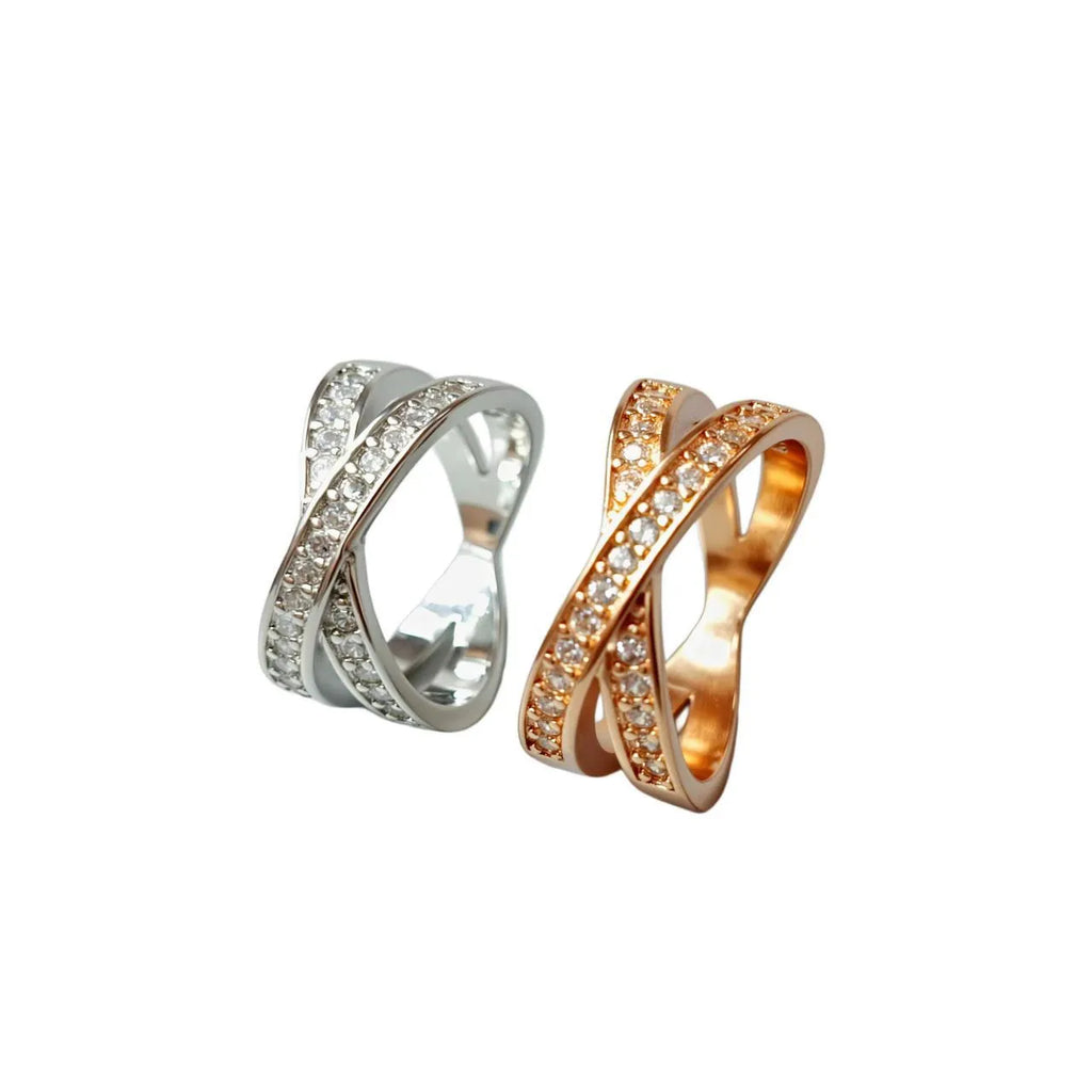 Close-up of a geometric cross ring on a hand, showing micro-inlaid zircon detail on a silver electroplated band.