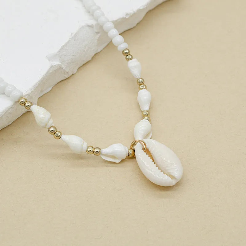 White electroplated shell necklace with conch bead mother-of-pearl pendant on a regular chain.