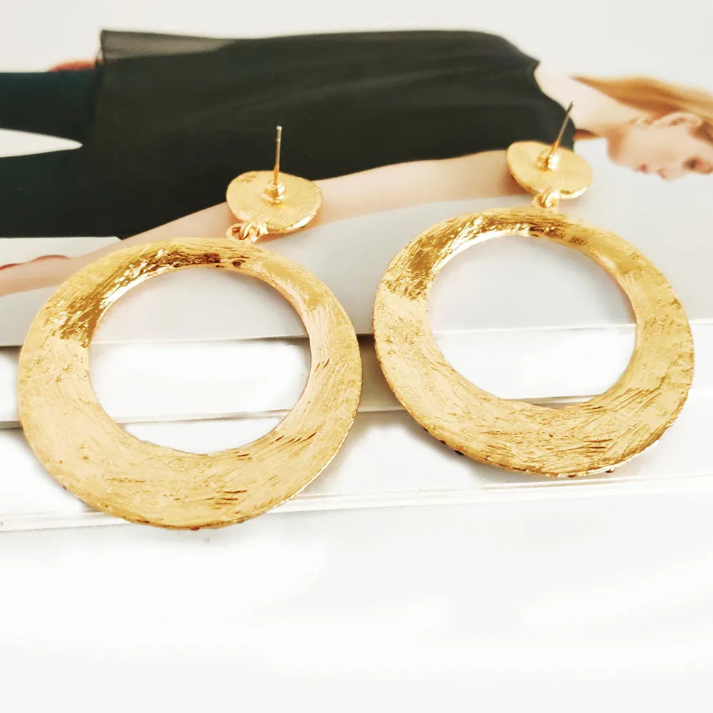 A pair of large round cartoon pendant earrings made from metal alloy, shown in a colour finish.