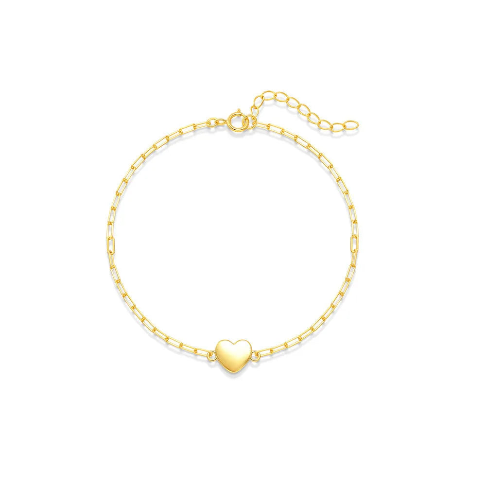 Close-up of a women's sterling silver bracelet with a glossy gold heart charm and lobster clasp.
