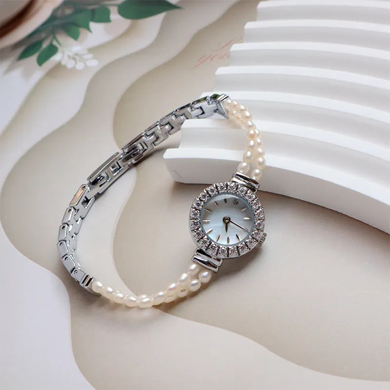 Light gold women's bracelet watch with freshwater pearls and a round 18mm dial.