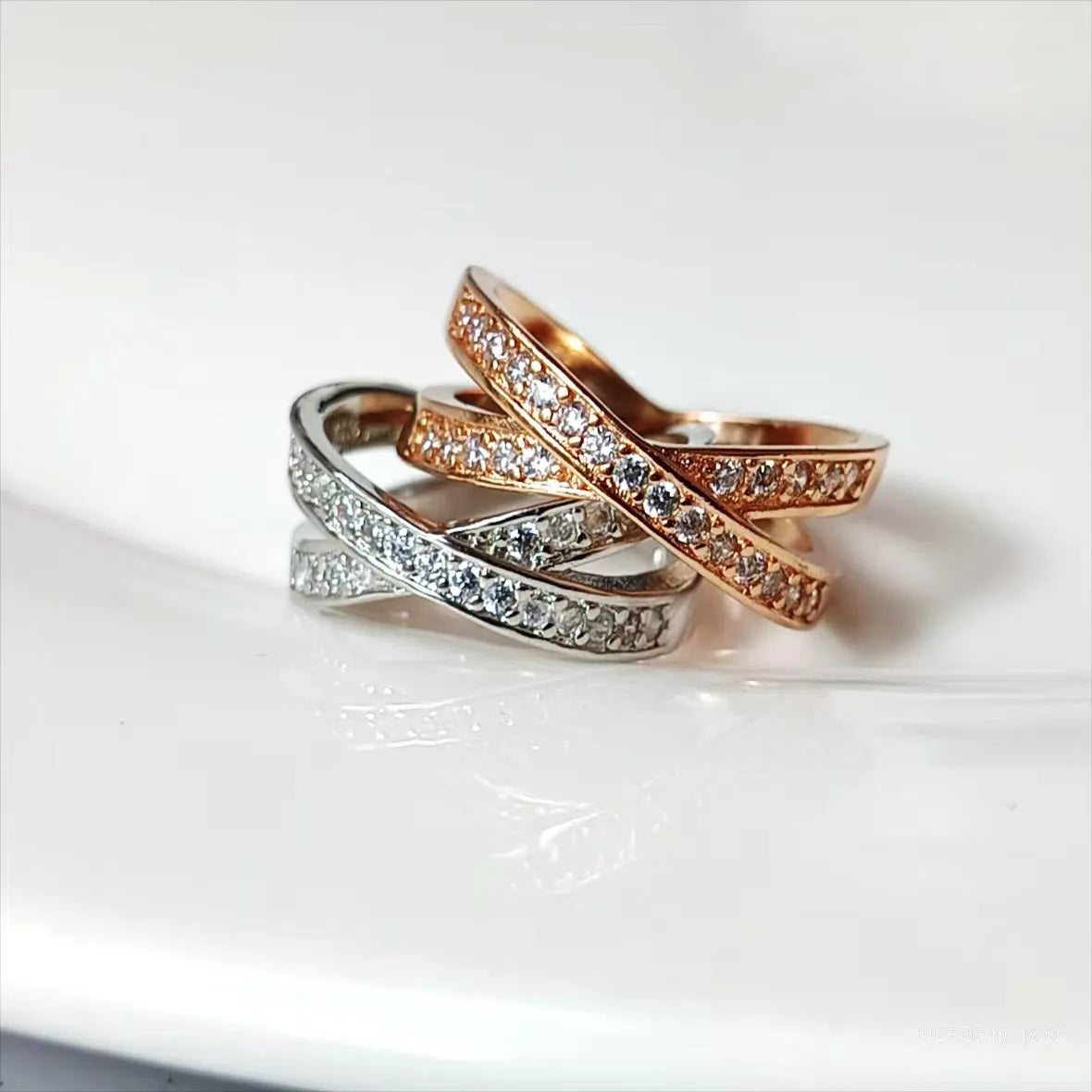 Close-up of a geometric cross ring on a hand, showing micro-inlaid zircon detail on a silver electroplated band.
