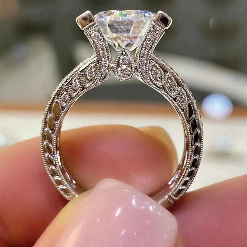 A geometric silver-tone women's ring with a round design element on a model's hand.