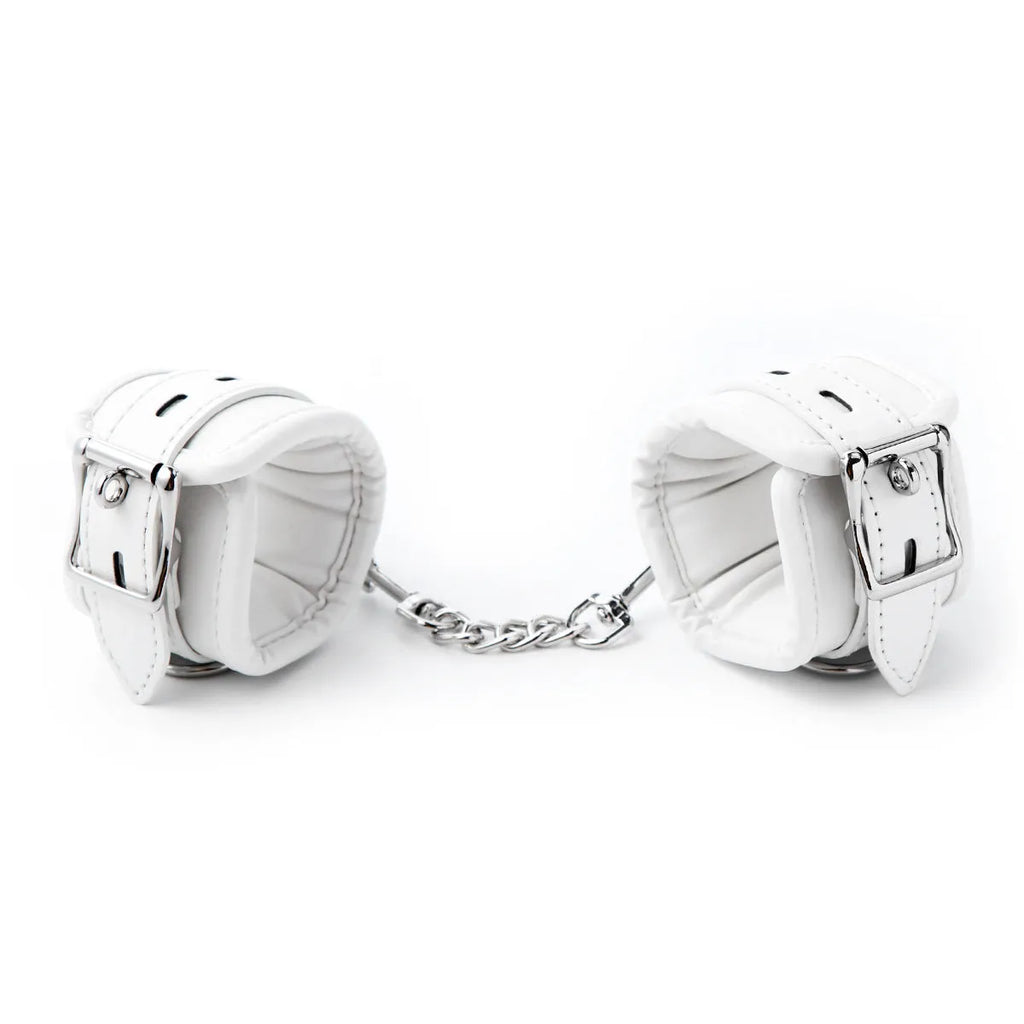 White PU sponge bondage handcuffs and foot cuffs with metal buckles on a nylon strap.