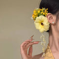 Handmade yellow and purple floral hair clip with pearl details and a tassel on a metal side clip.
