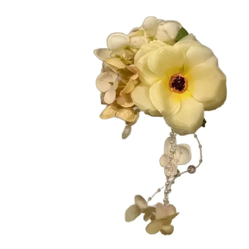 Handmade yellow and purple floral hair clip with pearl details and a tassel on a metal side clip.