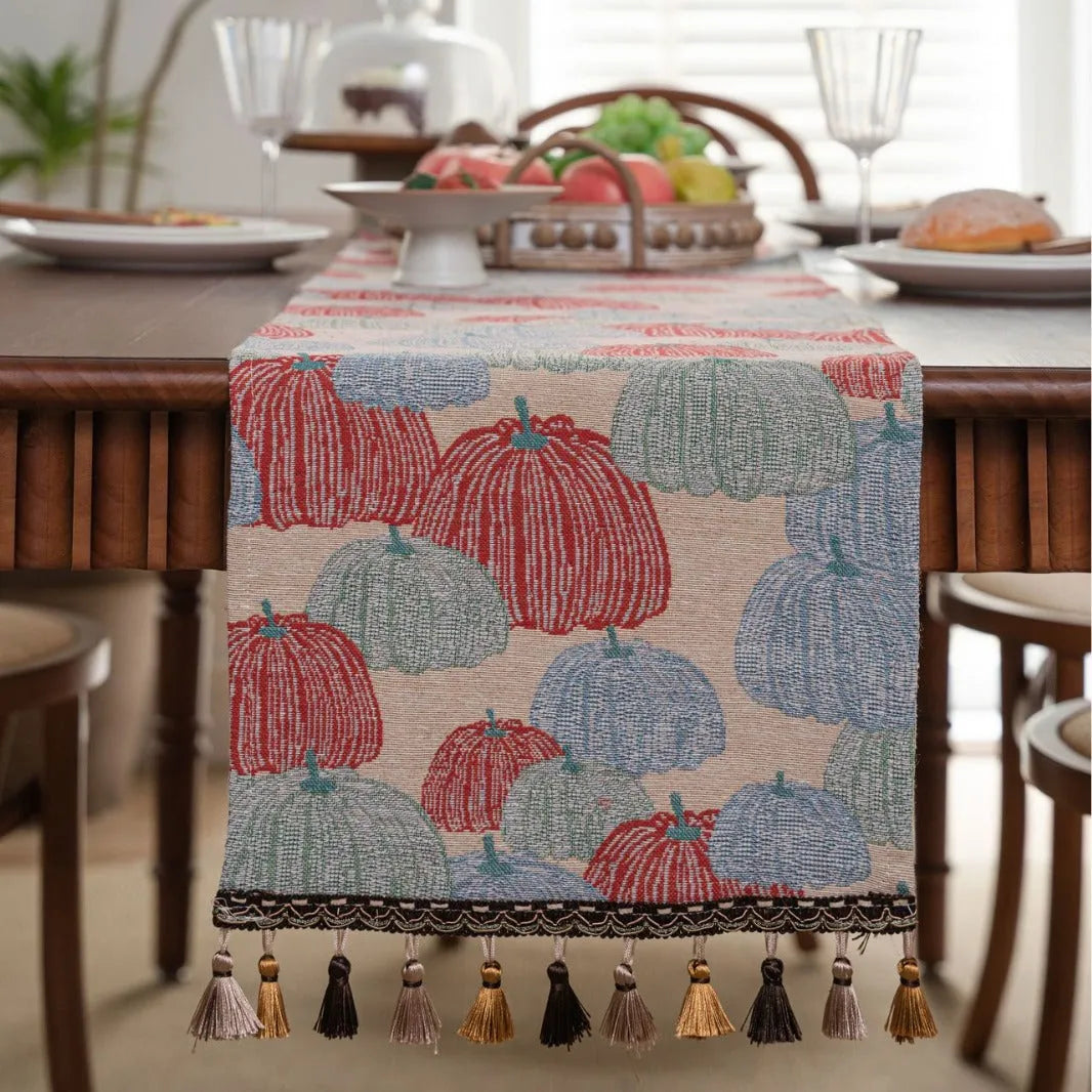 Long beige jacquard table runner with floral pattern and tassels draped on a wooden dining table.
