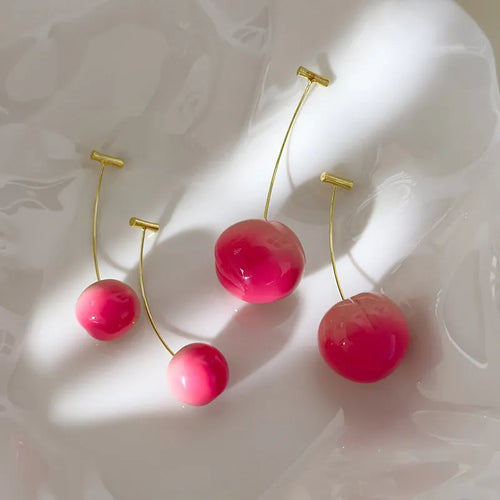 A pair of acrylic peach-shaped earrings with copper posts, shown in small and large size options.