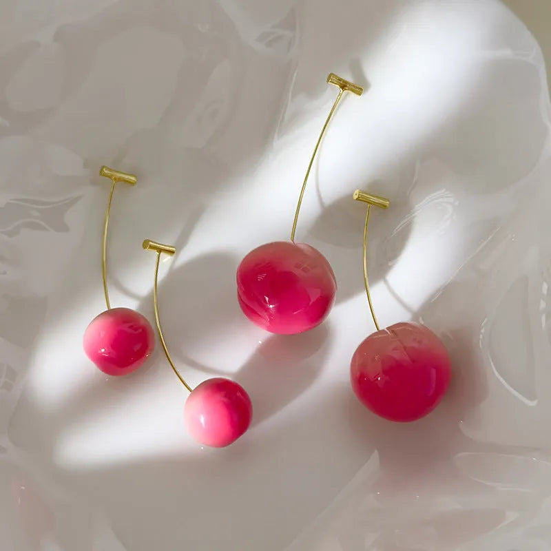 A pair of peach-shaped acrylic earrings on a white background, shown in two colour options.