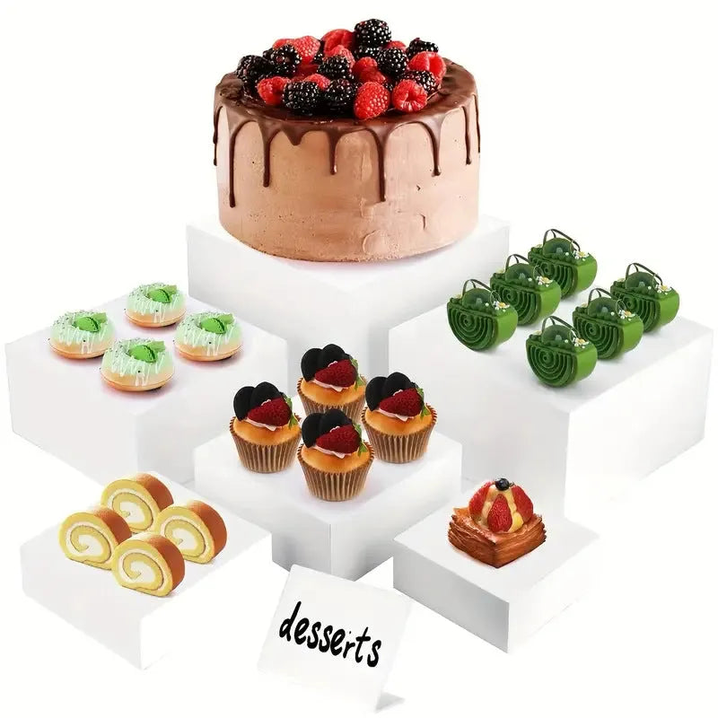 Set of six white plastic dessert display stands arranged on a tabletop.
