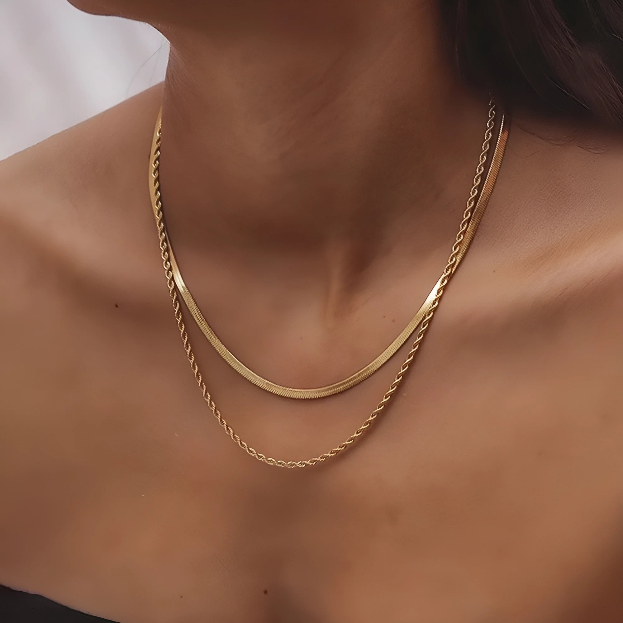 Close-up of a women's silver geometric twist necklace on an adjustable snake chain, showing its layered stainless steel pendant.