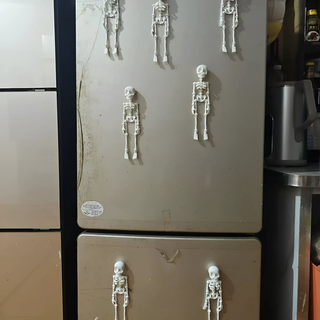3D printed white Halloween skull refrigerator magnet ornament on a metallic surface.