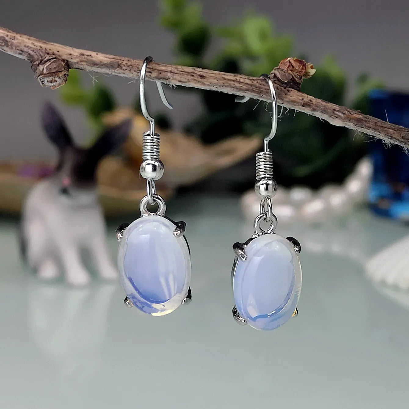 A pair of retro drop-shaped alloy earrings with electroplated moonstone opal colour and ellipse design elements.