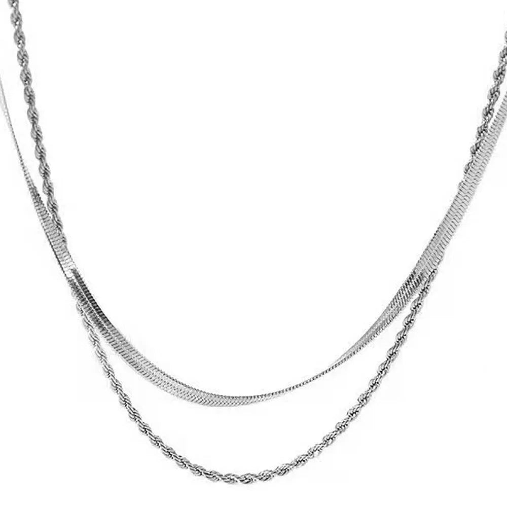 Close-up of a women's silver geometric twist necklace on an adjustable snake chain, showing its layered stainless steel pendant.