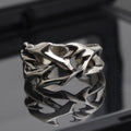 Copper men's ring with thorn and flower design on a geometric band, showing adjustable opening.