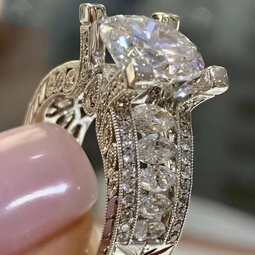 A geometric silver-tone women's ring with a round design element on a model's hand.