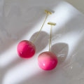 A pair of peach-shaped acrylic earrings on a white background, shown in two colour options.