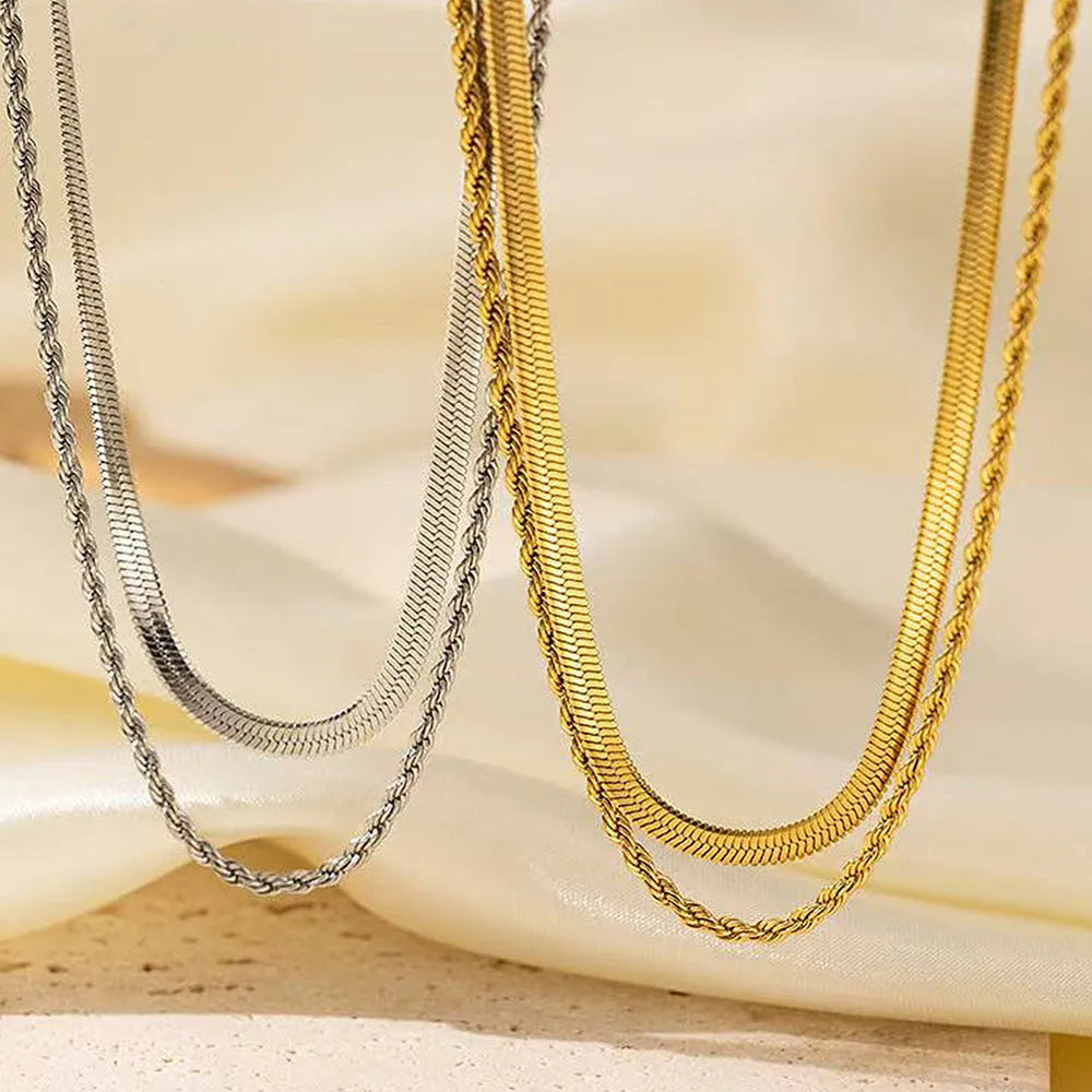 Close-up of a women's silver geometric twist necklace on an adjustable snake chain, showing its layered stainless steel pendant.