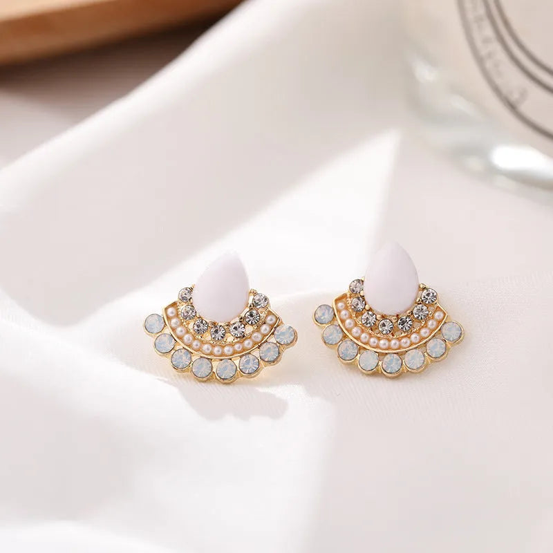 Close-up of a pair of women's retro fan-shaped silver earrings with rhinestone details on a geometric alloy setting.