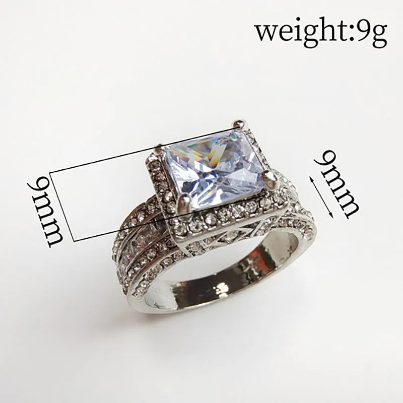 A geometric silver-tone women's ring with a round design element on a model's hand.
