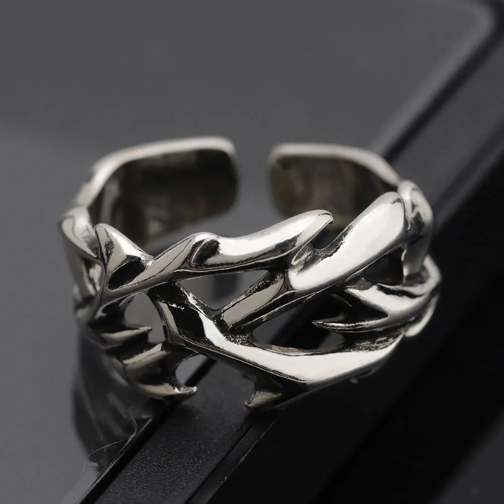 Copper men's ring with thorn and flower design on a geometric band, showing adjustable opening.