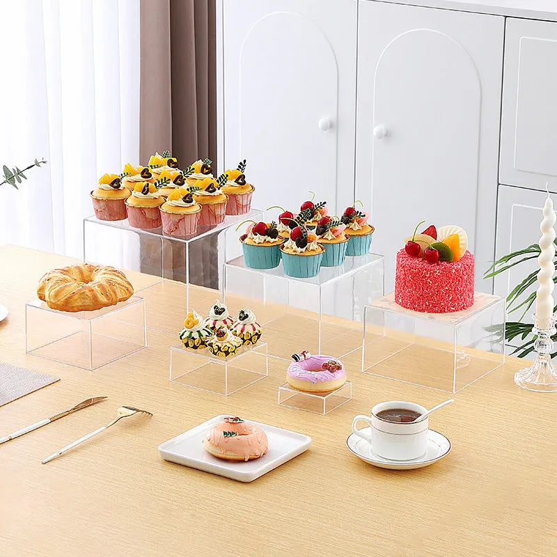 Set of six white plastic dessert display stands arranged on a tabletop.