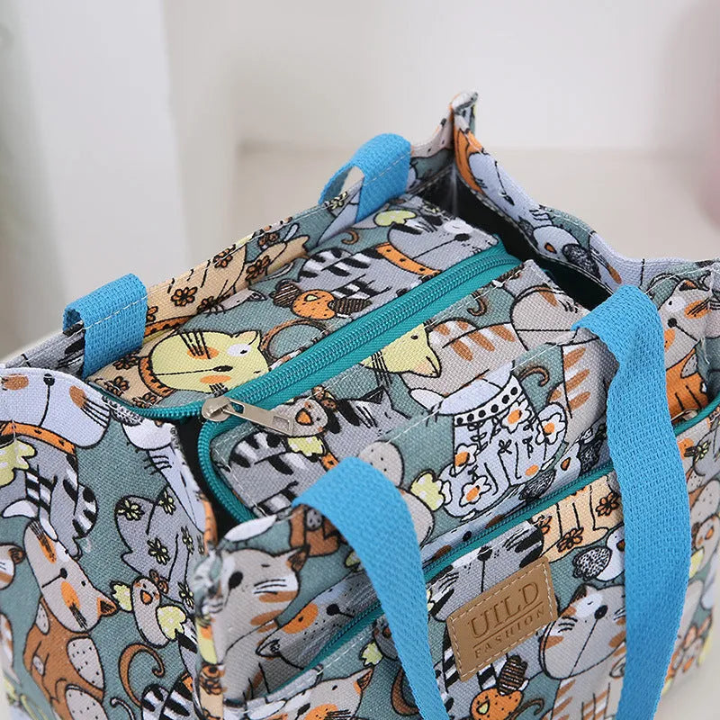 Women's printed canvas tote bag with aluminium handles in a floral or cat design.