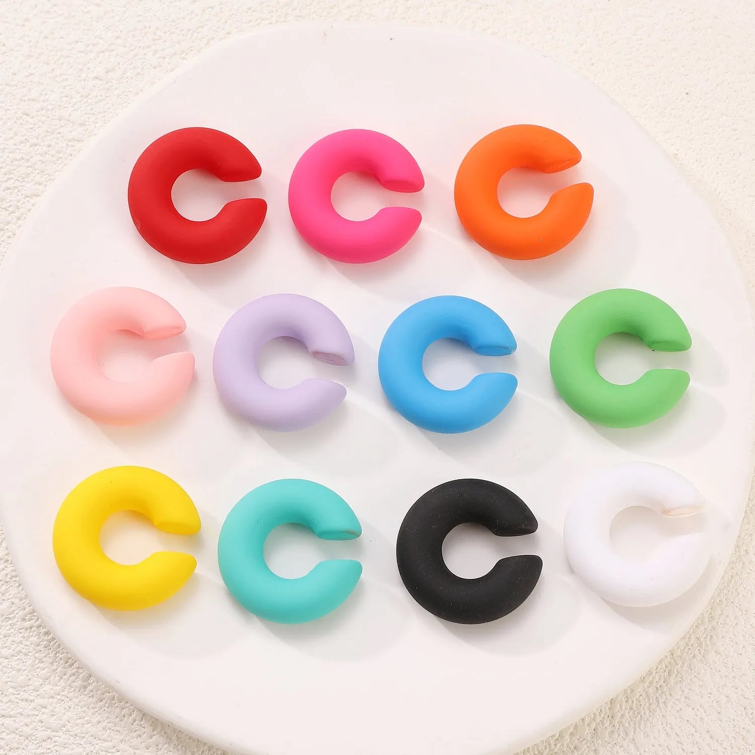 Close-up of matte finish, coarse round C-shaped clip-on earrings for women in a candy colour.