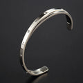 Open-ended stainless steel bracelet with inlaid zircon stones in a love-themed design, shown in rose gold colour.